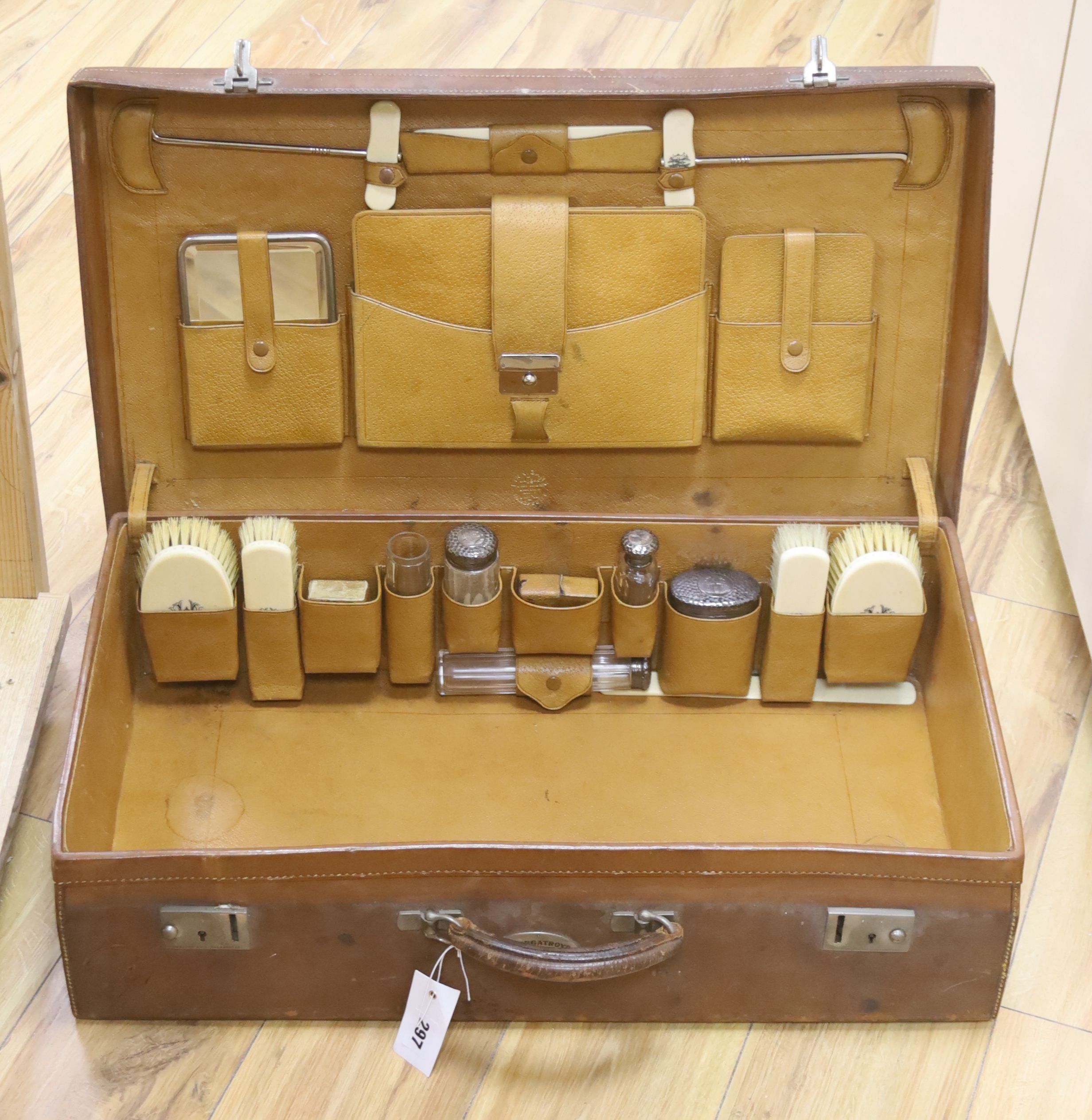 Finnigans of Manchester. A leather case fitted with silver mounted and ivory dressing accessories